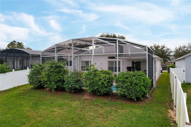 back of property featuring a lawn and glass enclosure