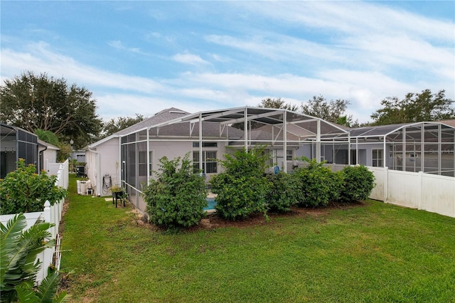 rear view of house with a lawn and glass enclosure