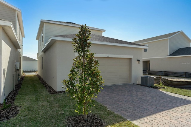 view of home's exterior featuring a garage, a lawn, and central air condition unit