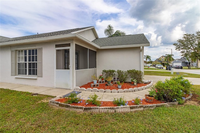 view of property exterior featuring a lawn and a sunroom