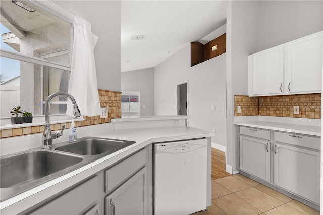 kitchen with decorative backsplash, white dishwasher, plenty of natural light, and light tile patterned floors