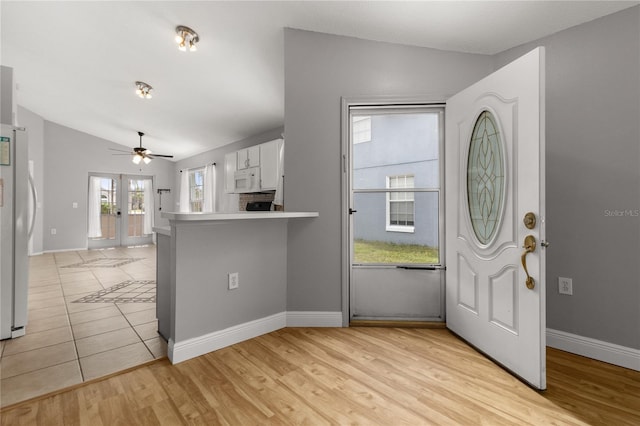 foyer featuring french doors, ceiling fan, lofted ceiling, and light wood-type flooring