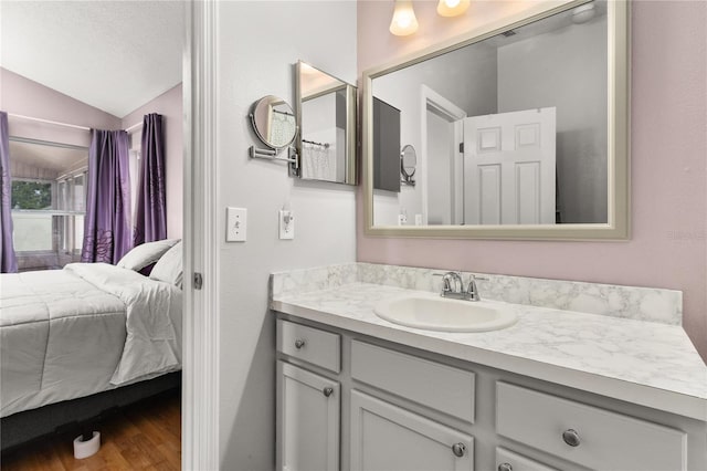 bathroom featuring vanity, hardwood / wood-style floors, and vaulted ceiling