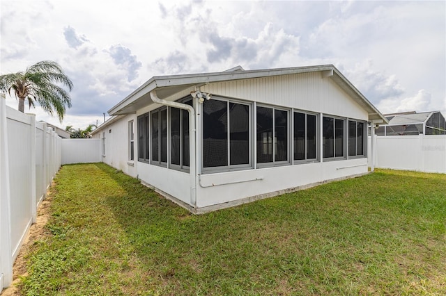 back of house with a sunroom and a lawn