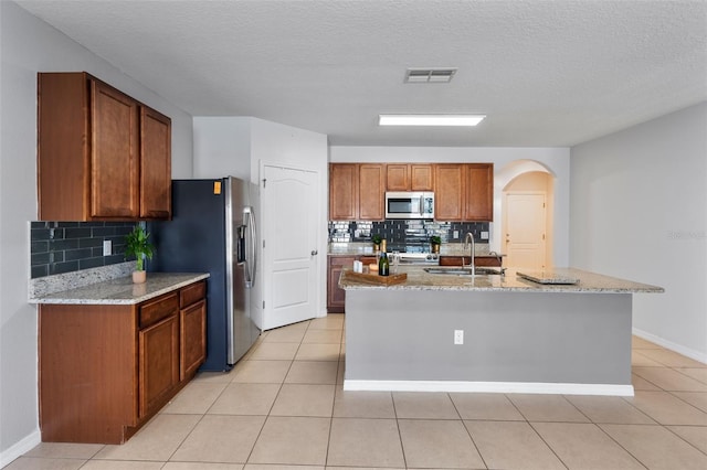 kitchen with backsplash, stainless steel appliances, sink, and a kitchen island with sink