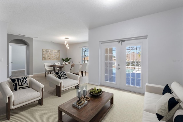 living room with a healthy amount of sunlight, a textured ceiling, and french doors