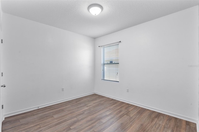 spare room featuring wood-type flooring and a textured ceiling