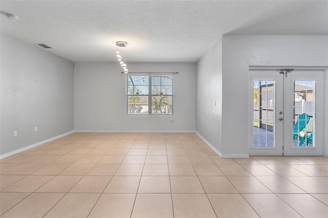 spare room featuring light tile patterned flooring, a textured ceiling, and french doors
