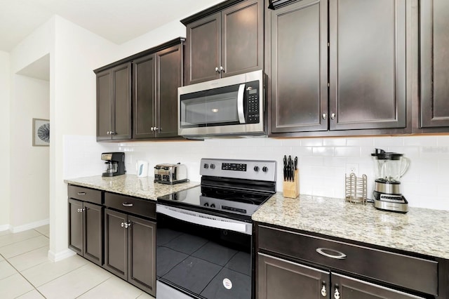 kitchen with decorative backsplash, light tile patterned floors, appliances with stainless steel finishes, light stone countertops, and dark brown cabinetry