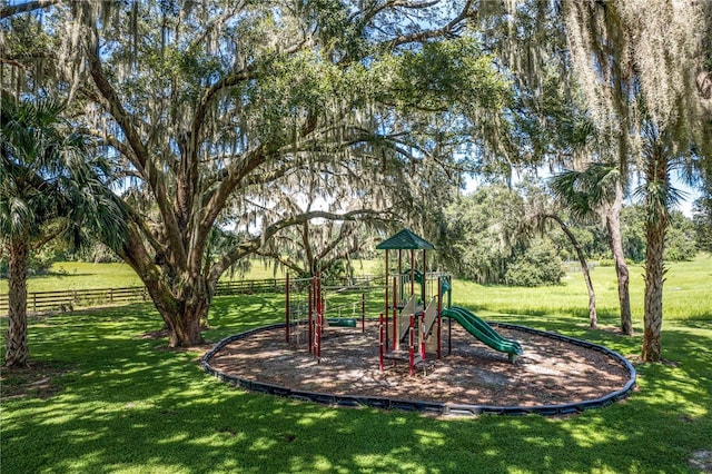 community jungle gym featuring a yard and fence