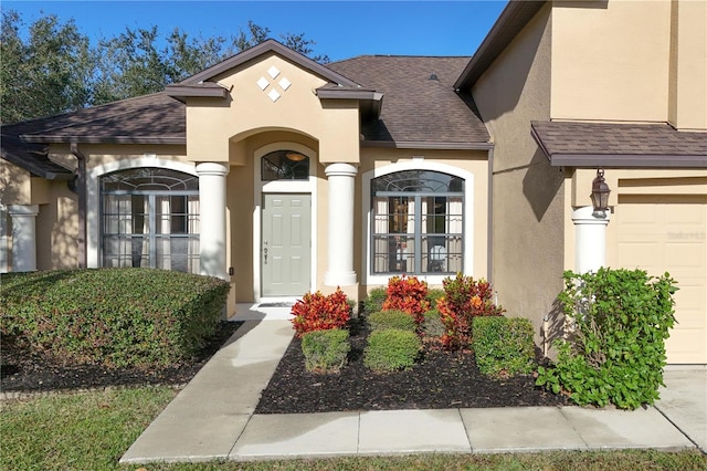 property entrance with a garage, roof with shingles, and stucco siding