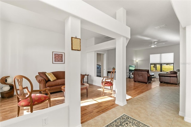 living room with light wood-style floors, baseboards, and a ceiling fan