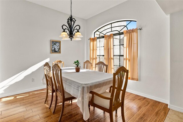 dining space with a notable chandelier, light wood-style flooring, and baseboards