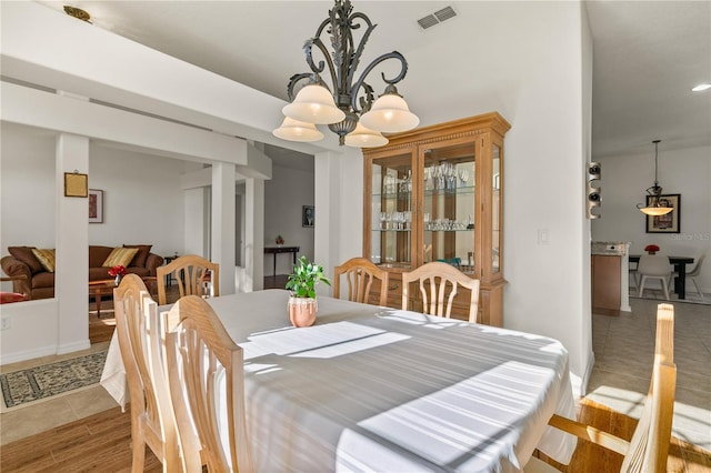 dining room featuring light wood-style floors, baseboards, visible vents, and a chandelier