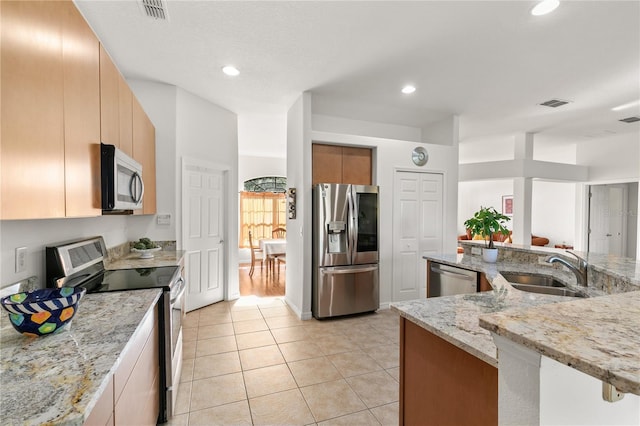 kitchen with stainless steel appliances, recessed lighting, light tile patterned flooring, a sink, and light stone countertops