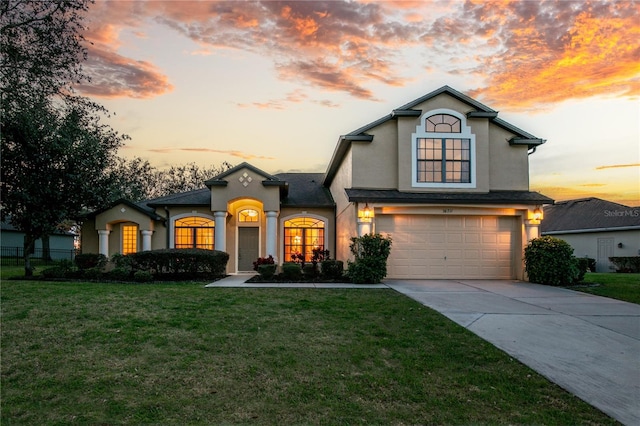 view of front of house with a lawn, driveway, an attached garage, and stucco siding