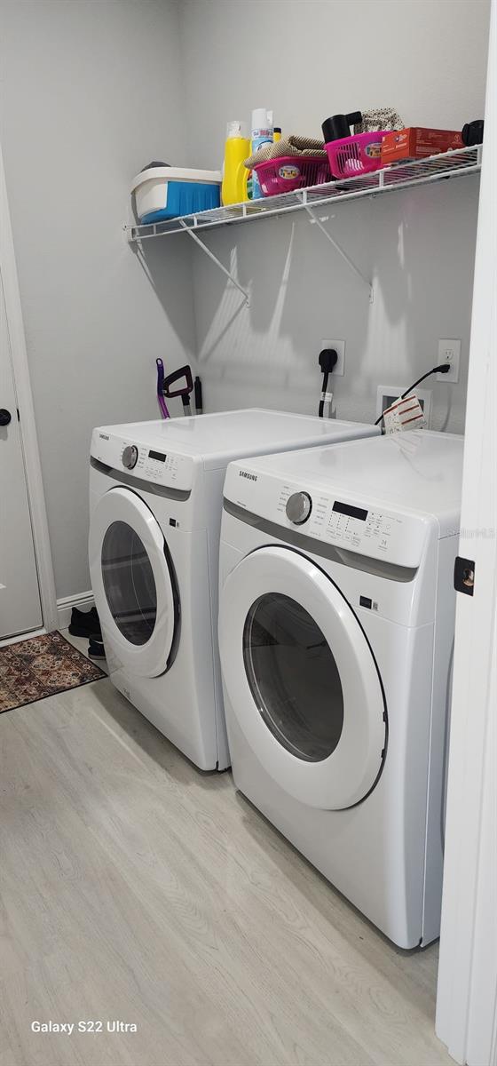 clothes washing area with light hardwood / wood-style flooring and washer and clothes dryer