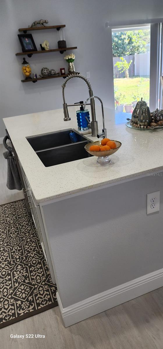 interior details featuring sink, light stone counters, and hardwood / wood-style flooring