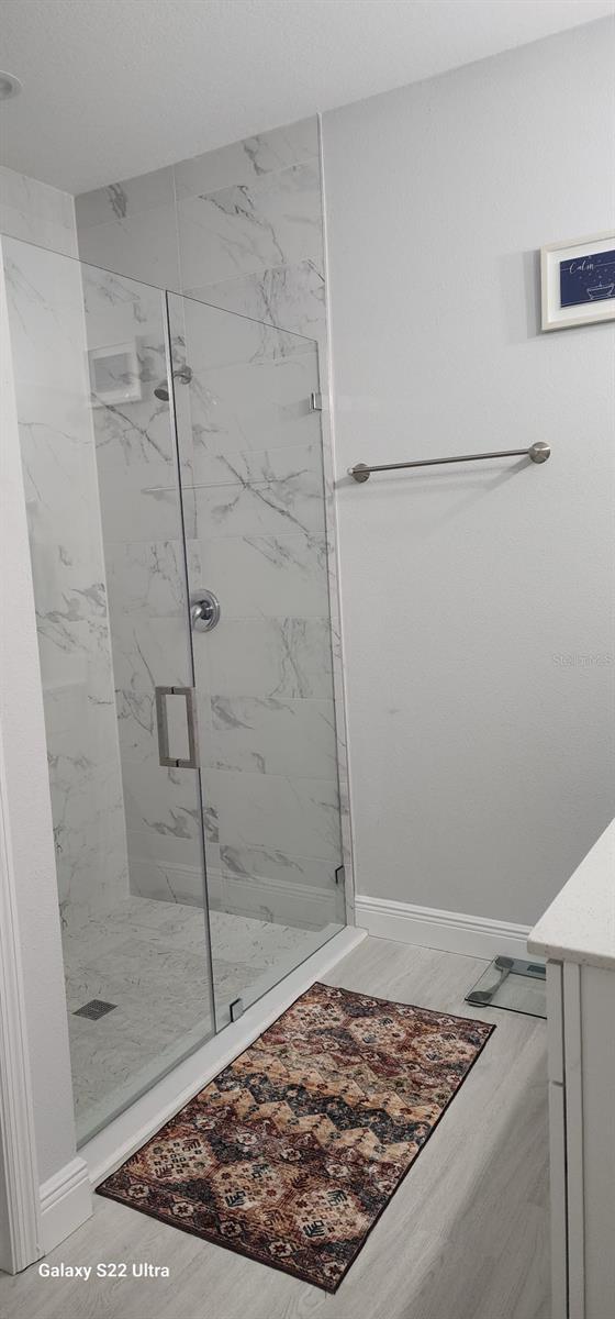 bathroom featuring vanity, a shower with shower door, and wood-type flooring