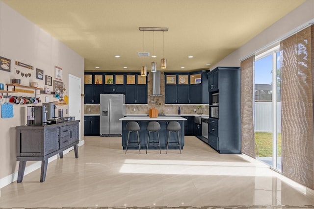 kitchen featuring hanging light fixtures, stainless steel fridge with ice dispenser, a breakfast bar, tasteful backsplash, and blue cabinetry