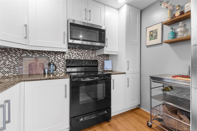 kitchen with backsplash, light wood-type flooring, black electric range, and white cabinets