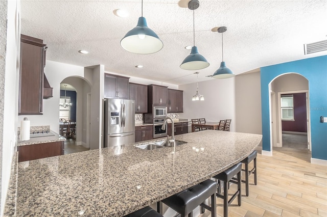 kitchen featuring light hardwood / wood-style flooring, dark brown cabinets, sink, a breakfast bar, and appliances with stainless steel finishes