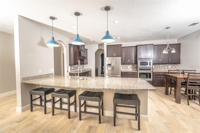 kitchen with sink, appliances with stainless steel finishes, kitchen peninsula, and pendant lighting