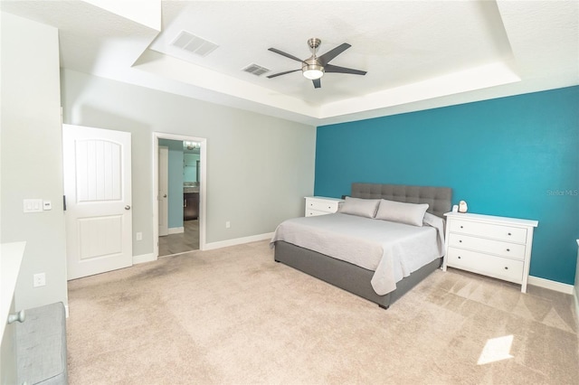 bedroom featuring ceiling fan, a raised ceiling, and light carpet