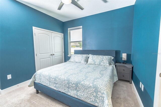 bedroom with light carpet, a textured ceiling, a closet, and ceiling fan