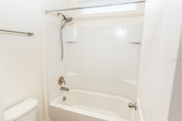 bathroom featuring toilet and tiled shower / bath