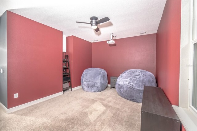 sitting room featuring light carpet, a textured ceiling, and ceiling fan