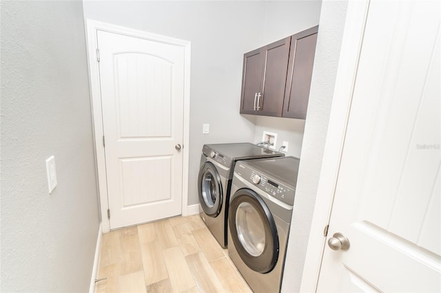 laundry area with cabinets, light hardwood / wood-style flooring, and separate washer and dryer