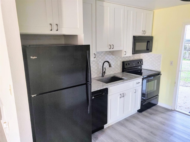 kitchen featuring backsplash, sink, black appliances, white cabinetry, and light hardwood / wood-style floors