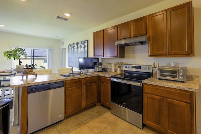 kitchen with kitchen peninsula, light tile patterned floors, sink, and appliances with stainless steel finishes