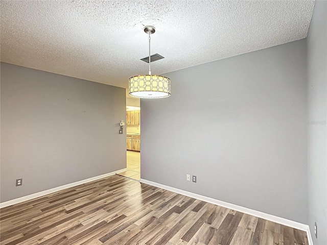 empty room featuring wood-type flooring and a textured ceiling