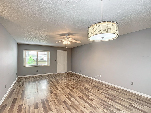 unfurnished room with a textured ceiling, wood-type flooring, and ceiling fan