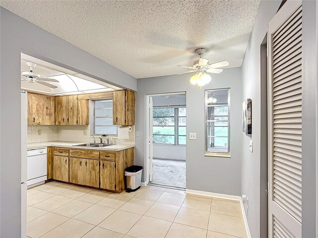 kitchen featuring white dishwasher, sink, light tile patterned floors, a textured ceiling, and ceiling fan