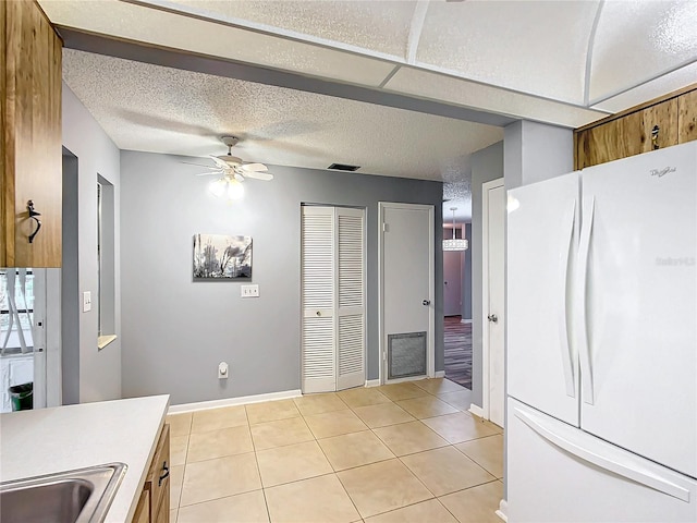 kitchen featuring white fridge, ceiling fan, light tile patterned floors, and sink