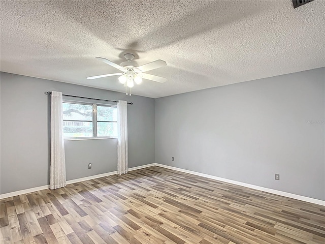 empty room with ceiling fan, hardwood / wood-style flooring, and a textured ceiling