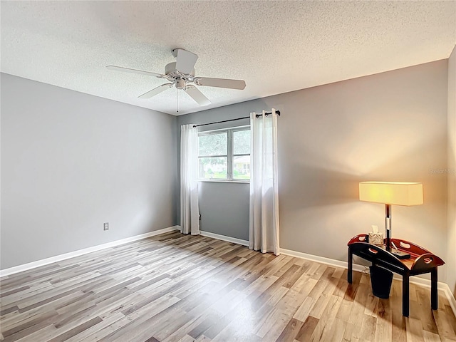 empty room with ceiling fan, a textured ceiling, and light hardwood / wood-style flooring