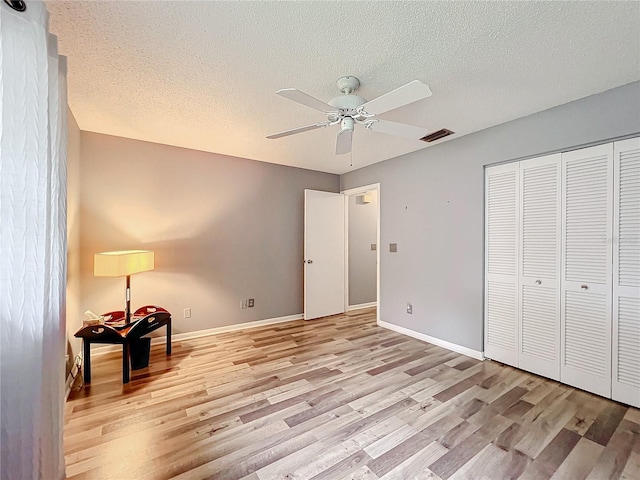 bedroom featuring a closet, ceiling fan, a textured ceiling, and light hardwood / wood-style flooring