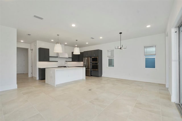 kitchen featuring an island with sink, appliances with stainless steel finishes, sink, and pendant lighting