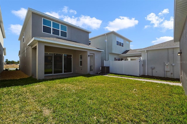 rear view of property with a yard and central AC