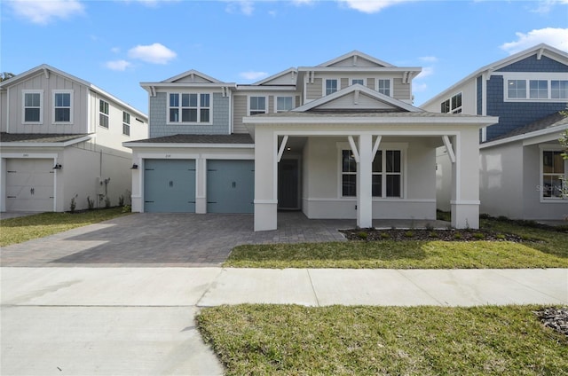 view of front of house with a porch, a front yard, a garage, and driveway