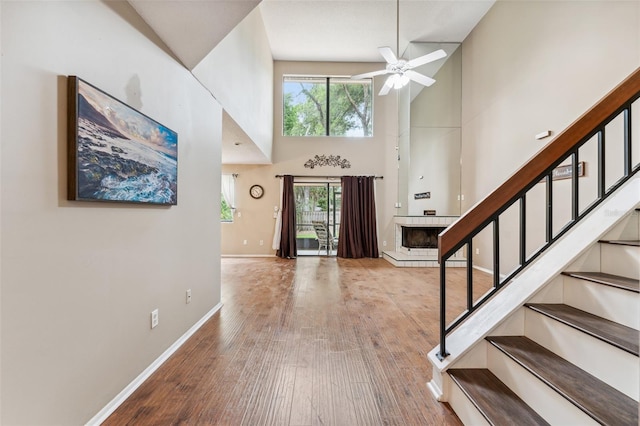 entryway featuring ceiling fan, a healthy amount of sunlight, a towering ceiling, and light hardwood / wood-style flooring