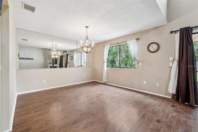 unfurnished dining area featuring a textured ceiling, dark hardwood / wood-style flooring, and an inviting chandelier