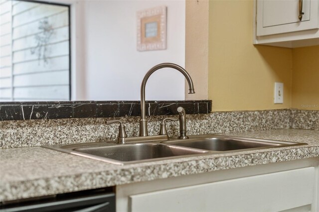 interior details featuring dishwasher, white cabinets, and sink