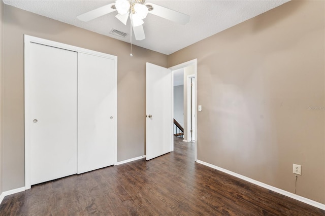 unfurnished bedroom with dark hardwood / wood-style flooring, a closet, a textured ceiling, and ceiling fan