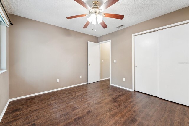 unfurnished bedroom featuring ceiling fan, a textured ceiling, and dark hardwood / wood-style flooring