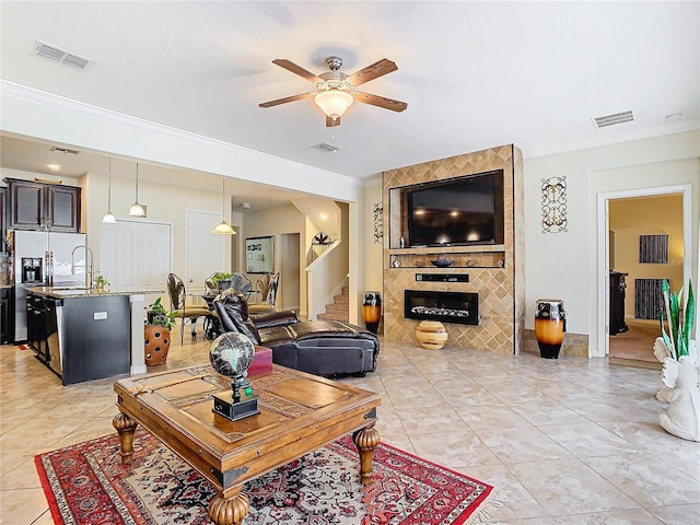 tiled living room featuring ornamental molding, sink, and ceiling fan